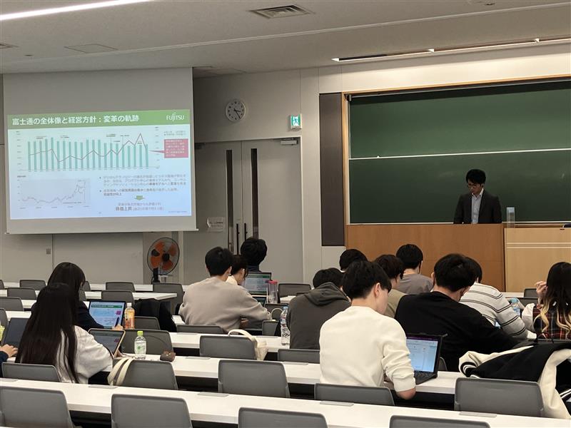 A briefing session by a Fujitsu employee for approximately 15 students in a university classroom